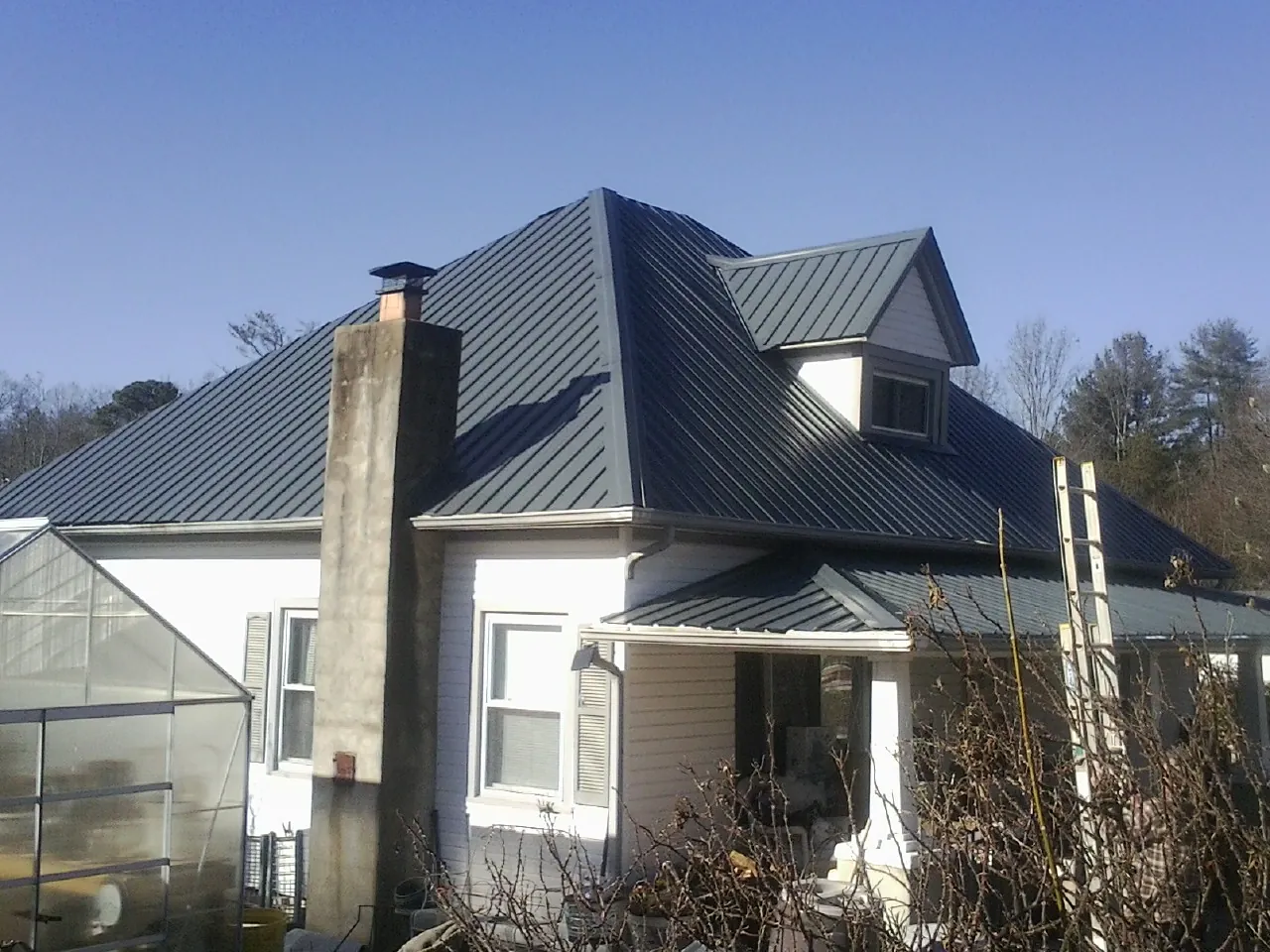 Dark blue standing seam metal roof on a white farmhouse with dormer — Slate & Tile Roof Repair by Roofing Brothers in Worth