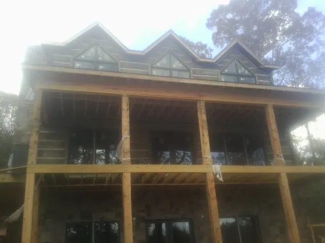 Dormers and porch framing on a large log home under construction — Roof Coating work by our crew in Worth