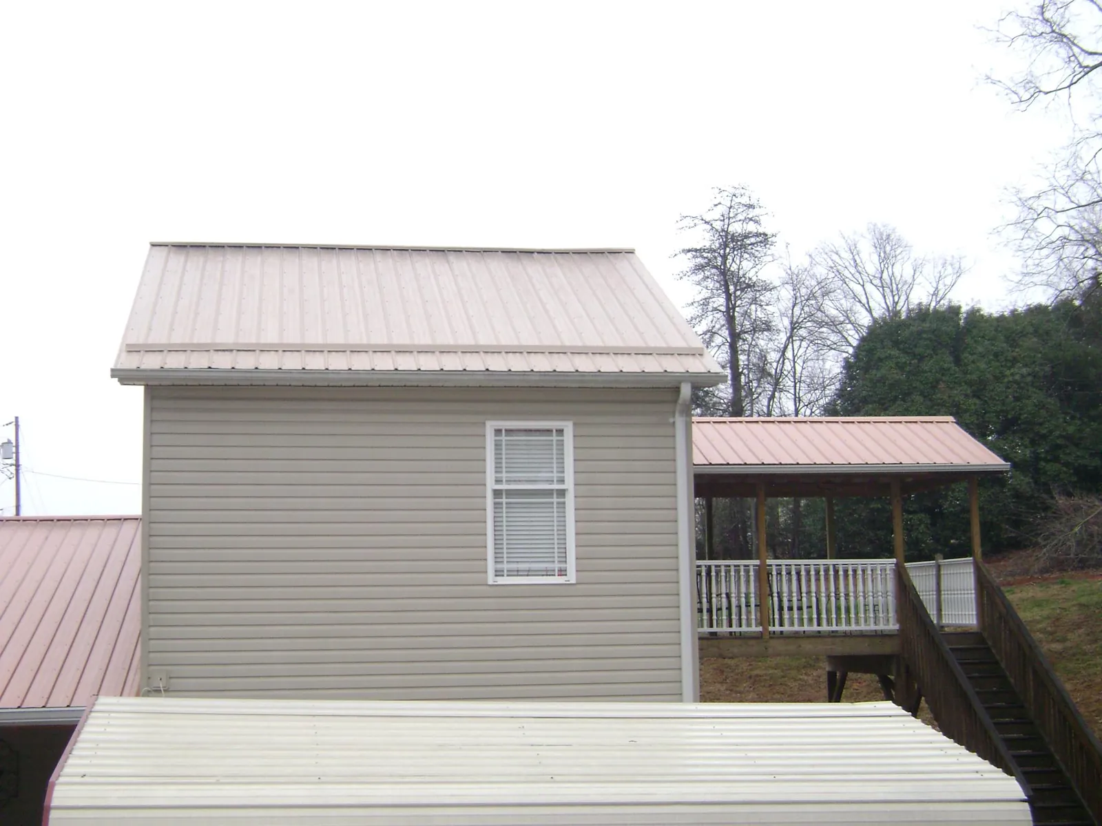 Tan metal roofs on a two story addition and attached porch, from a Roof Replacement job in Worth
